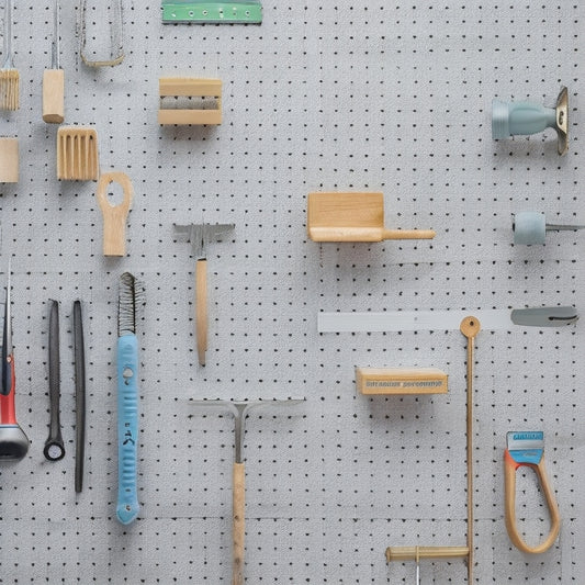 A well-organized pegboard with various tools and accessories, such as hammers, screwdrivers, pliers, and bins, against a bright white or light-gray background, with a subtle wood grain texture.